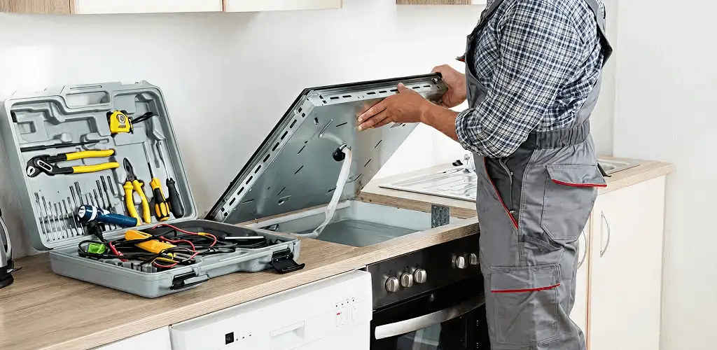 Handyman repairing a cooktop and checking wiring connections in Pueblo, CO