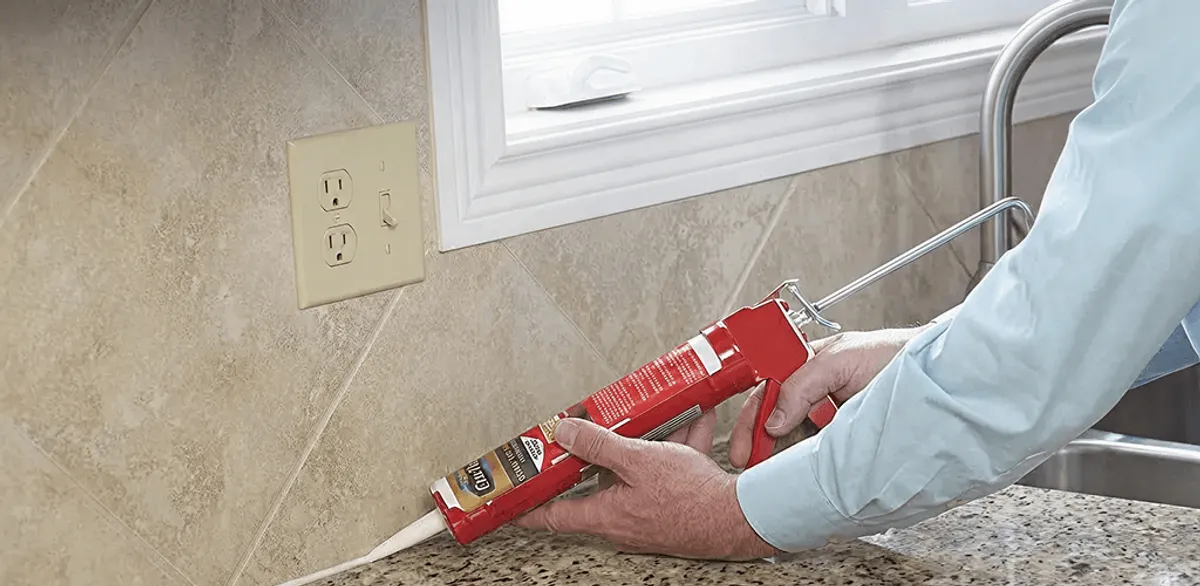 Handyman applying caulk along a kitchen backsplash and countertop seam in Pueblo, CO