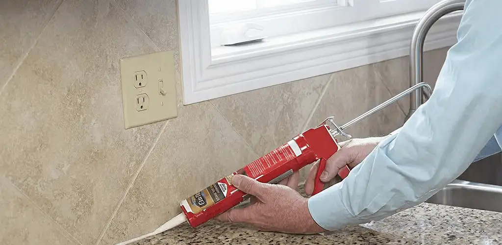 Handyman applying caulk along a kitchen backsplash and countertop seam in Pueblo, CO