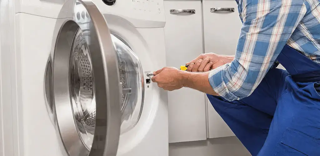 Handyman repairing a clothes dryer and checking electrical connections in Pueblo, CO
