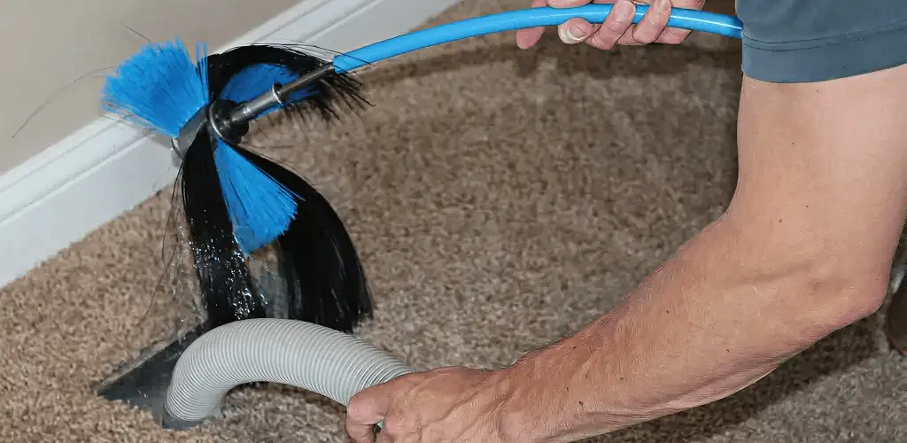 Dryer vent cleaning technician brushing lint from a vent line in Pueblo, CO