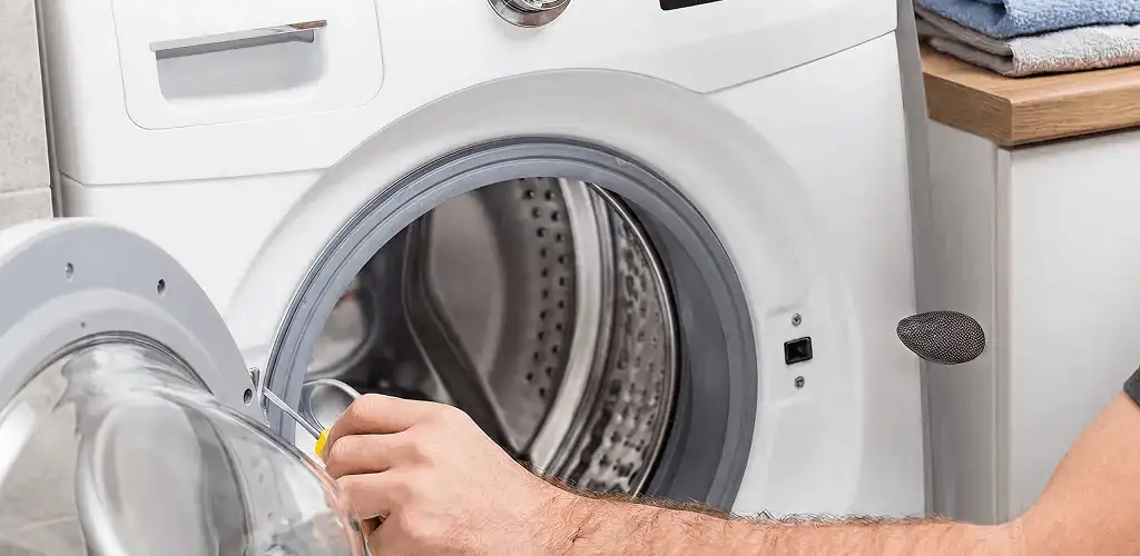 Handyman repairing a front-load washing machine and inspecting the drum in Pueblo, CO