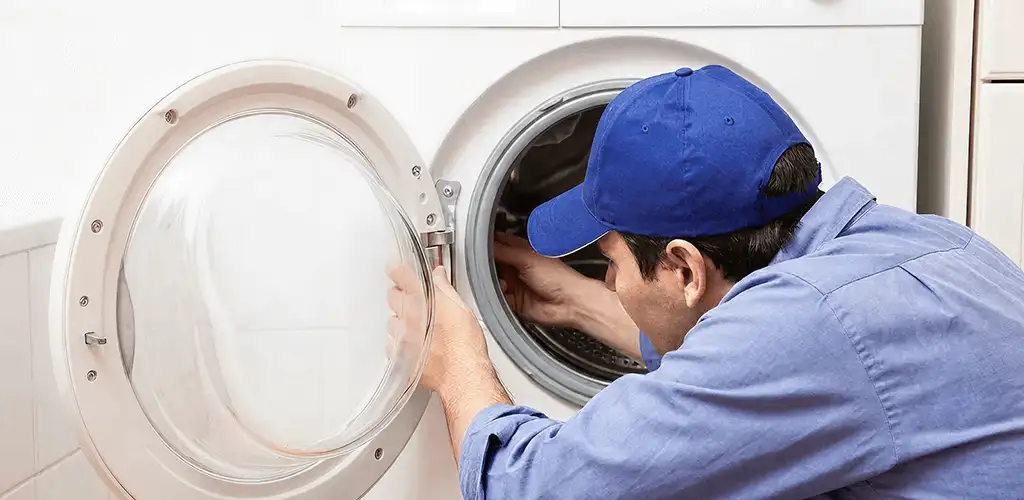 Washing machine repair handyman inspecting a front-load washer drum in Pueblo, CO