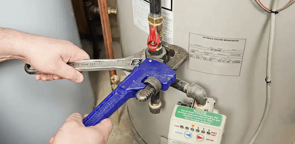 Water heater repair technician tightening the shutoff valve and supply line in Pueblo, CO